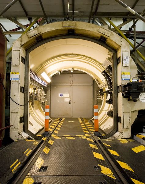 the inside of a train tunnel with yellow and white stripes on it's floor