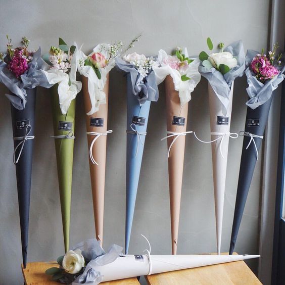 five different colored umbrellas with flowers tied to them on a table next to a window