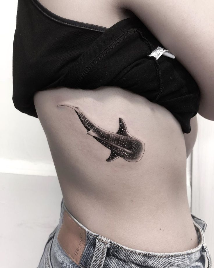 a black and white photo of a woman's stomach with a shark tattoo on it