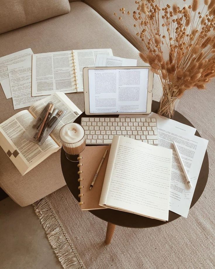 a table topped with lots of books and laptops next to a coffee table filled with papers