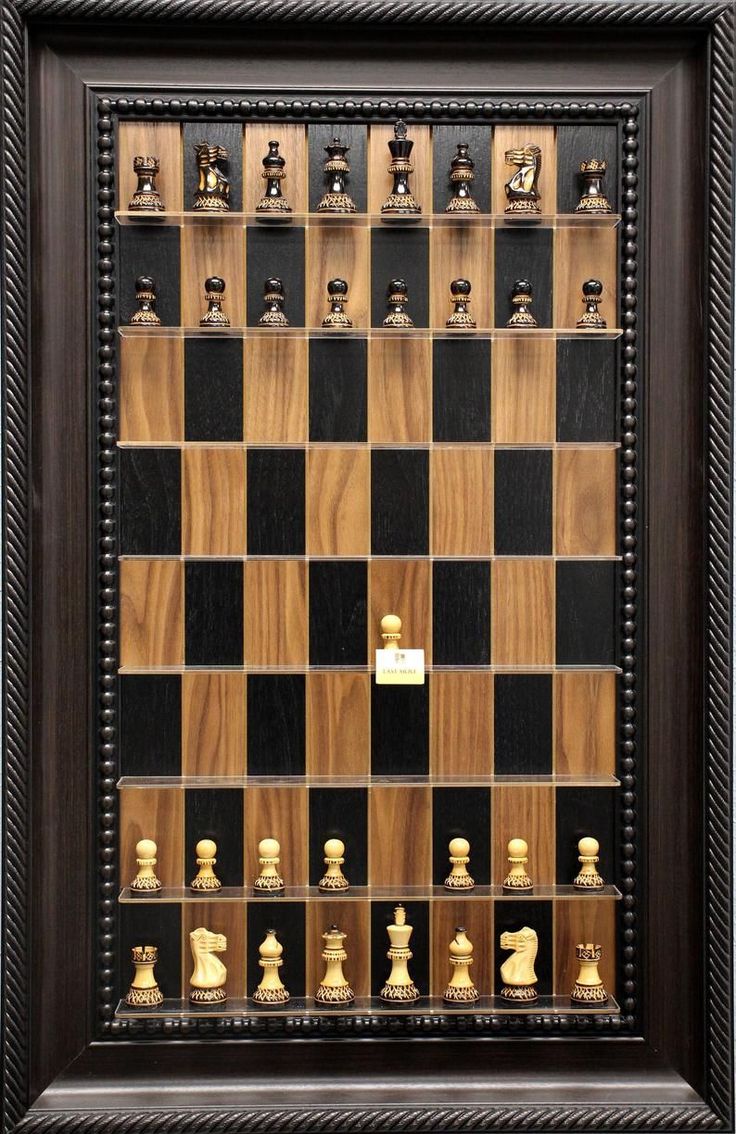 a framed chess board with many pieces on it and a black shadow box in the middle