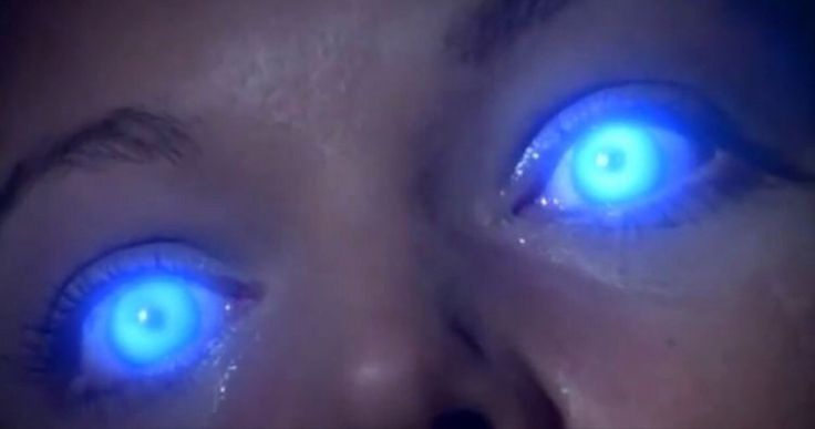 a woman with glowing blue eyes looking at the camera