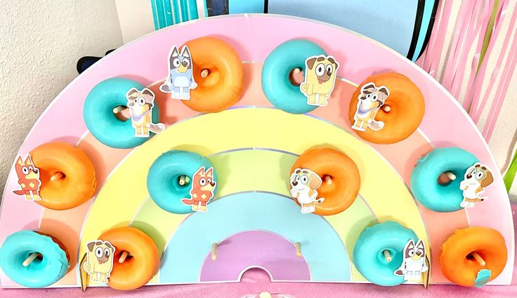 an assortment of donuts on a pink and blue plate with cartoon characters around them