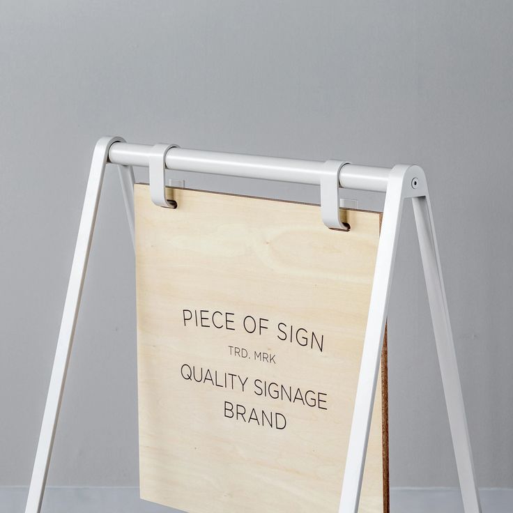 a piece of sign sitting on top of a wooden stand next to a white wall