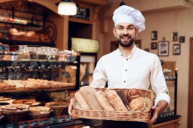 a man holding a basket full of bread in front of a bakery display filled with pastries