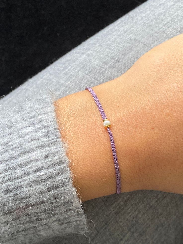 a woman's arm with a purple beaded bracelet on top of her wrist