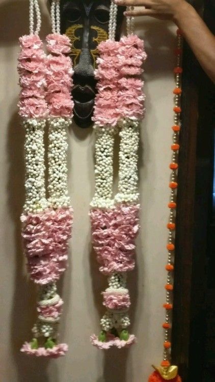 a wall hanging made out of pink and white flowers with chains attached to it's sides