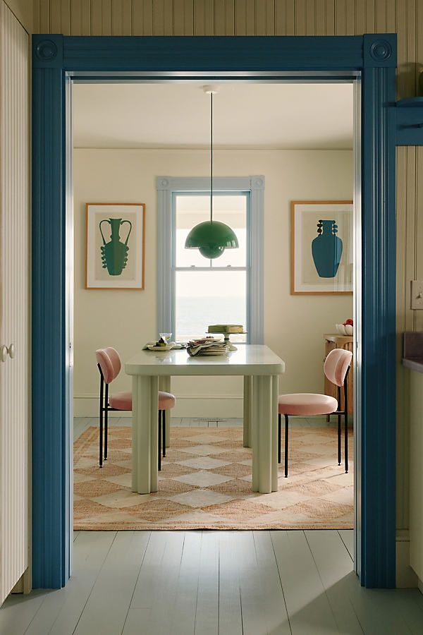 an open door leading to a dining room with chairs and a table in the center