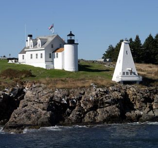 two lighthouses sit on the edge of a rocky cliff near an ocean and grassy area