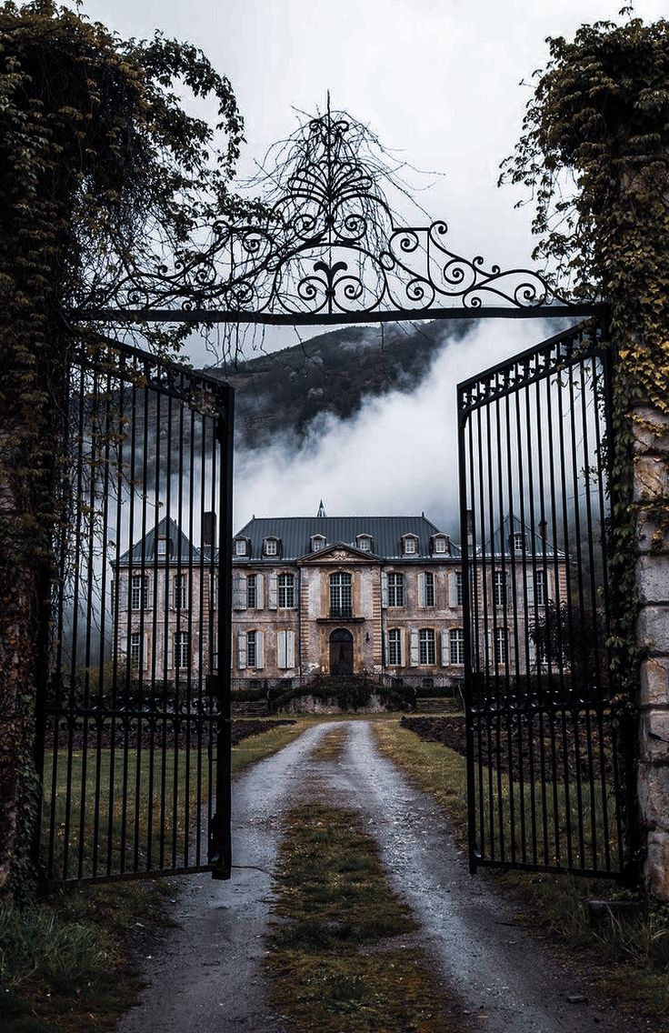 an open gate leading to a large house