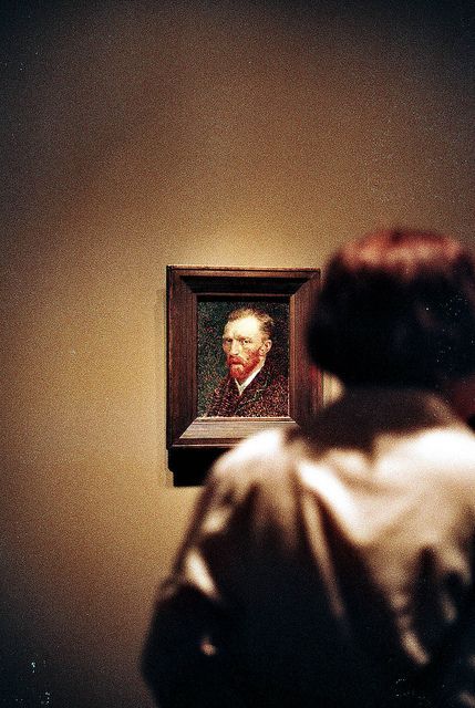 a woman looking at a painting on the wall