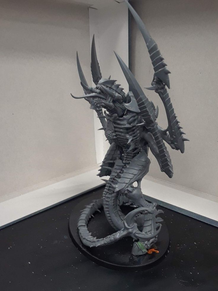 a statue of a dragon is on display in a room with white walls and black flooring