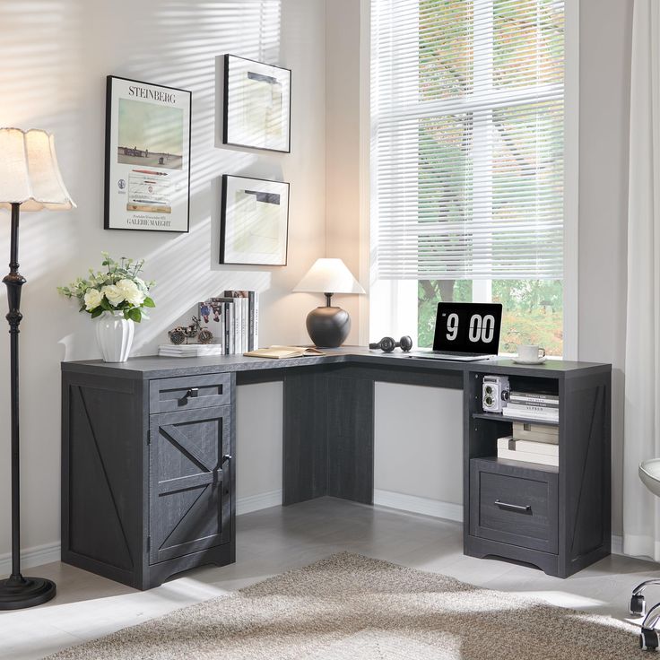 a corner desk with a computer on it in front of a window and some pictures