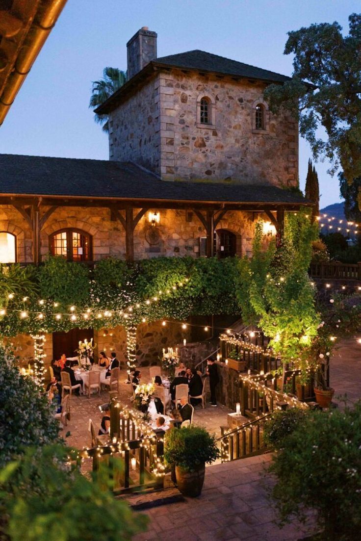 an outdoor dining area is lit up with fairy lights