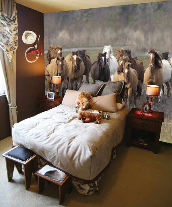 a dog laying on top of a bed in a room with horses painted on the wall