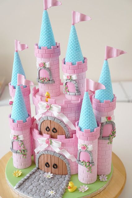 a cake that is shaped like a castle with pink and blue turrets on it's roof