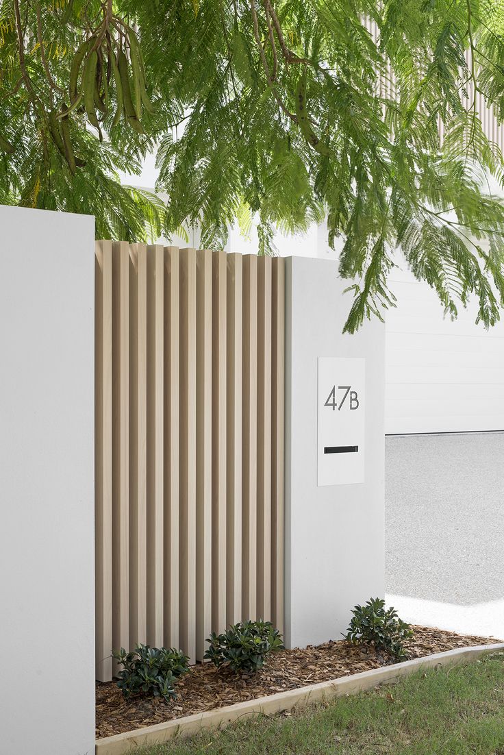 a tall white building sitting next to a lush green tree