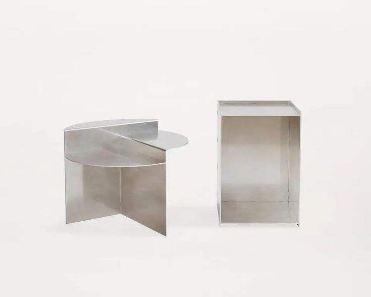 two metal tables sitting next to each other on a white surface