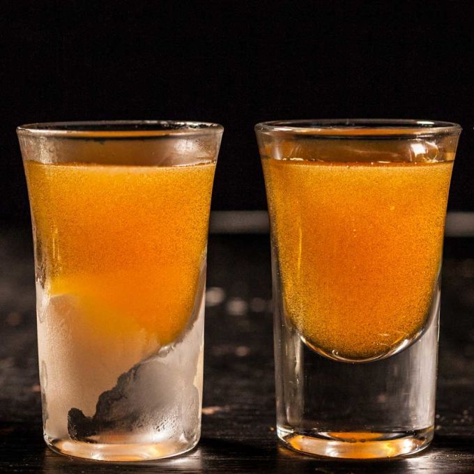 two glasses filled with liquid sitting on top of a table