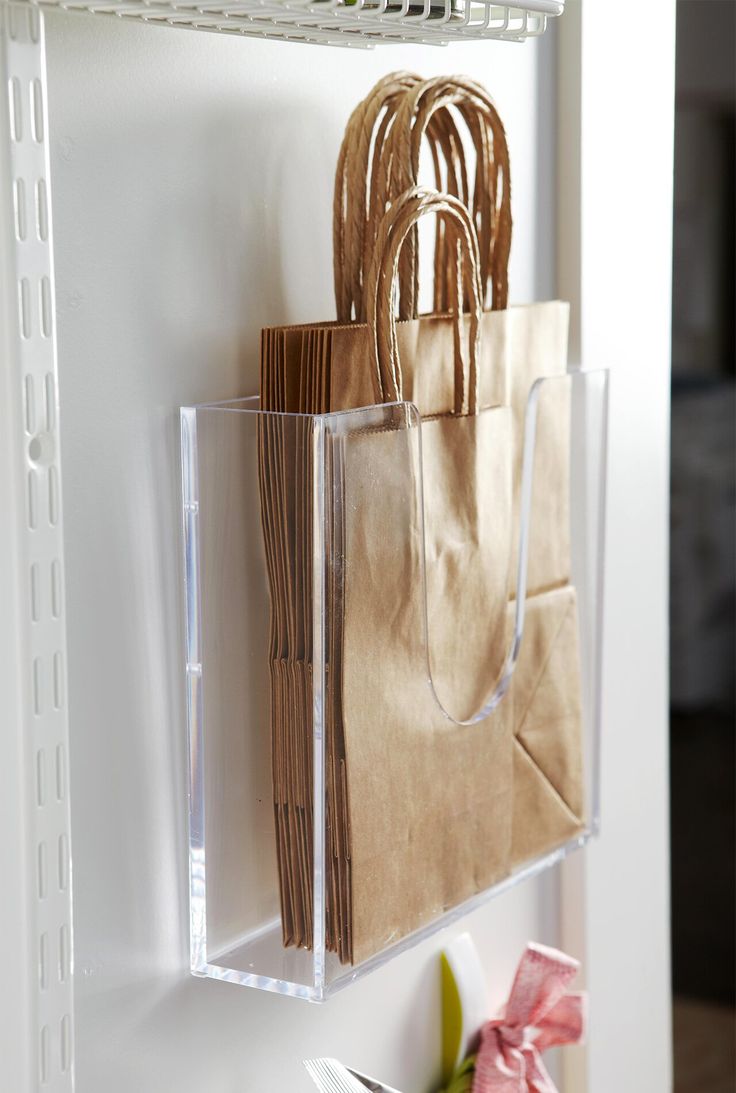 a bag hanging on the wall next to some paper bags and flowers in a vase