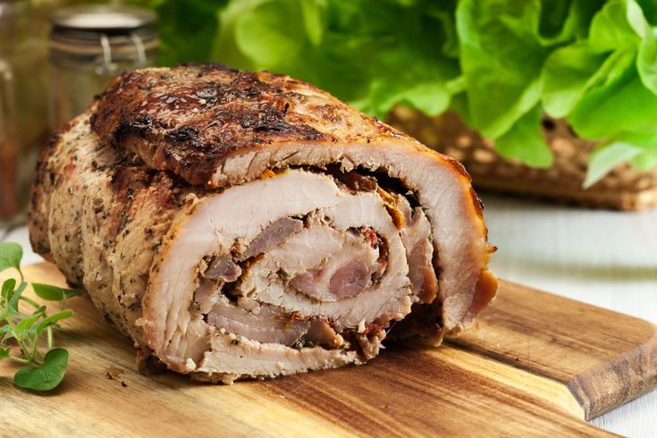 a sliced meat on a cutting board with lettuce in the backgroung