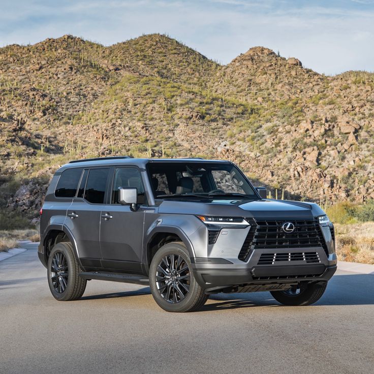 a grey suv is parked on the side of the road in front of some mountains