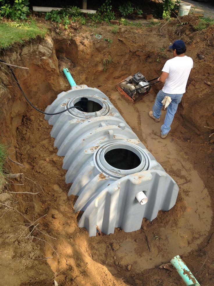 a man standing next to a pipe laying in the ground