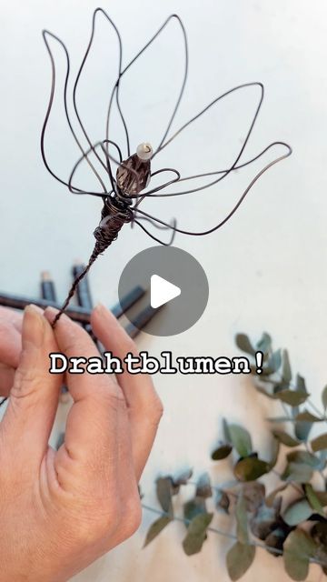 a person holding a wire dragon sculpture with the words draahtblumenn on it