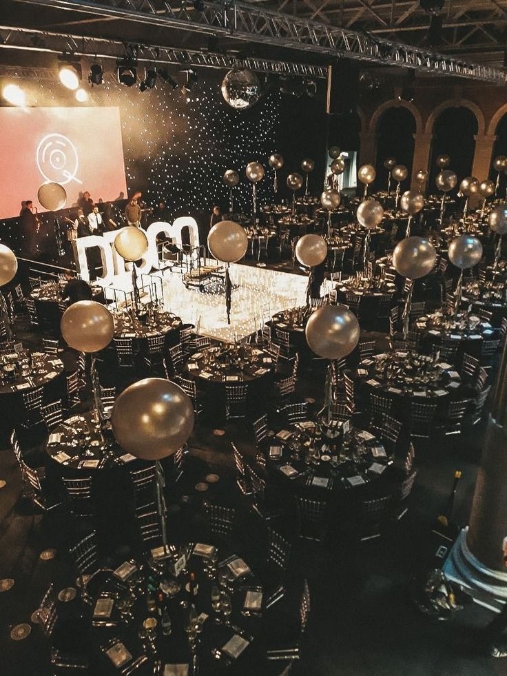 a large room filled with lots of tables and chairs covered in silver foil balloons on top of them