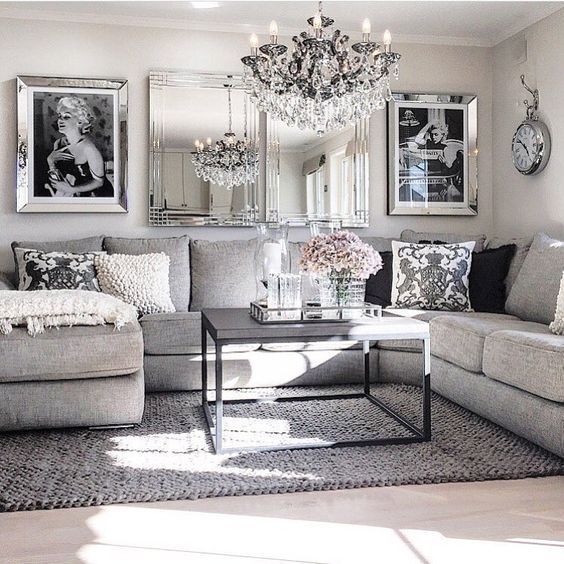 a living room filled with furniture and a chandelier hanging from the ceiling in front of a mirror