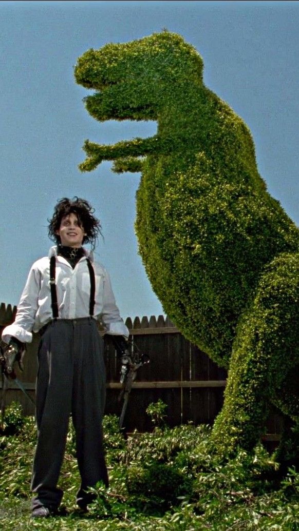 a man standing in front of a large fake alligator statue with his hands on his hips