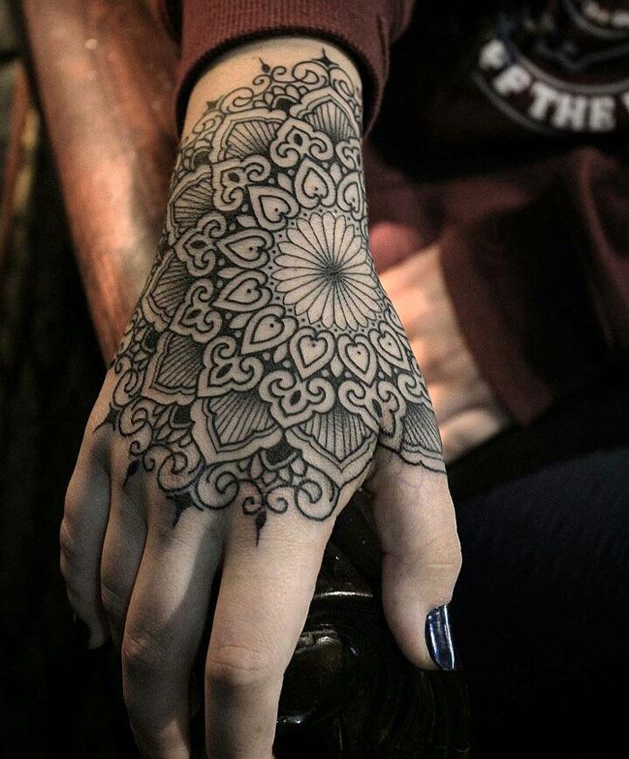 a person's hand with a tattoo on it, and the other hand has an intricate