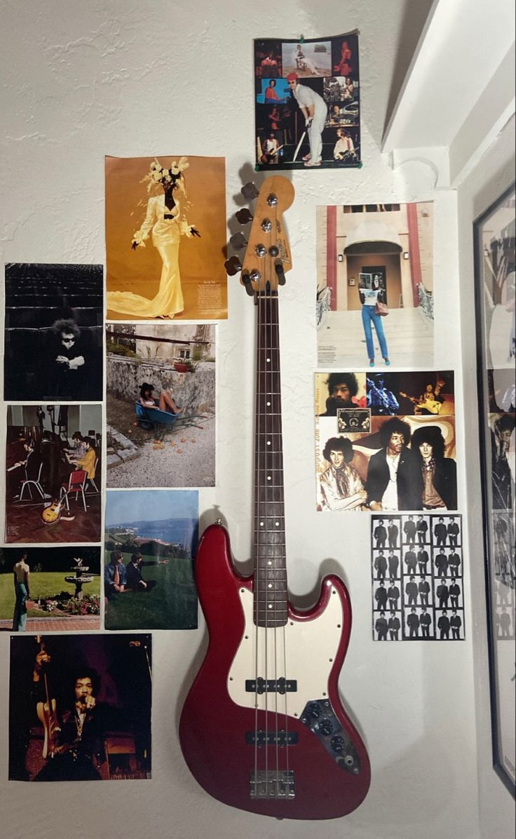 a red bass guitar sitting on top of a wall covered in pictures and magnets