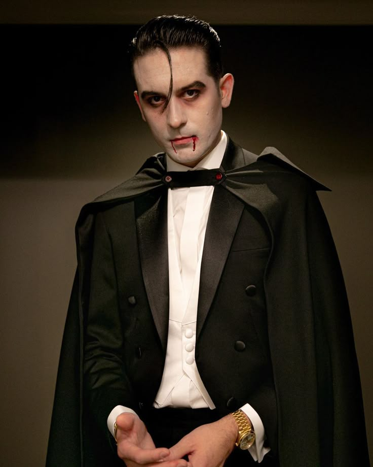 a man dressed as dracula in a tuxedo with his hands on his chest