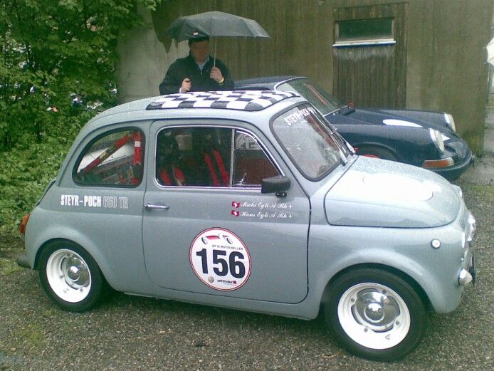 a small car with a man holding an umbrella