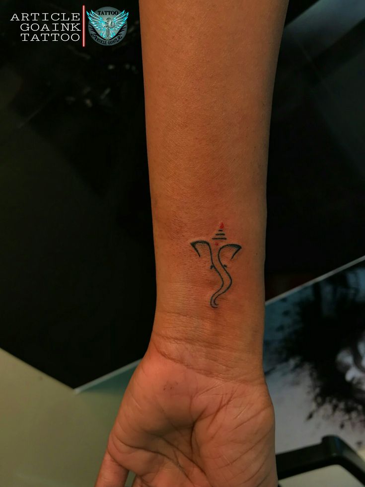 a small tattoo on the wrist of a person's hand, with an arrow in the middle