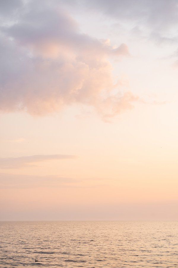 the sky is pink and cloudy over the ocean