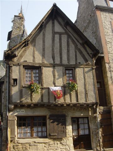 an old building with flowers on the windows and two story house next to each other