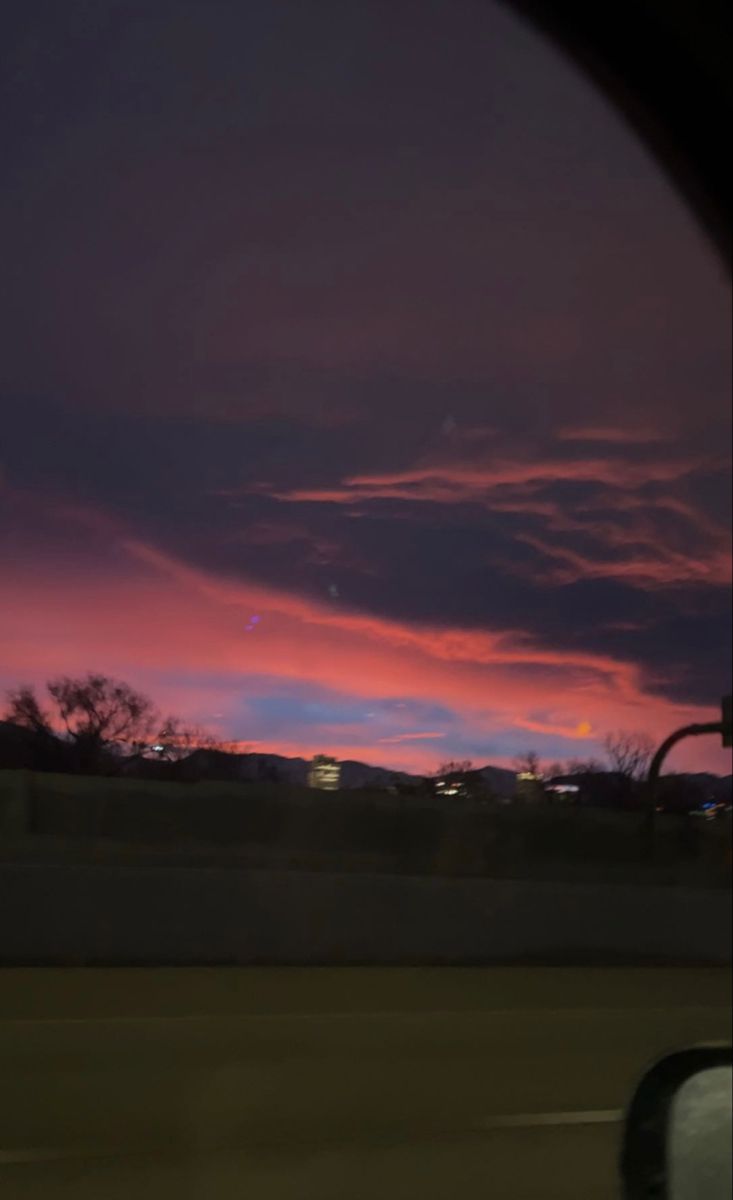 the sky is purple and pink as seen from inside a vehicle's side view mirror