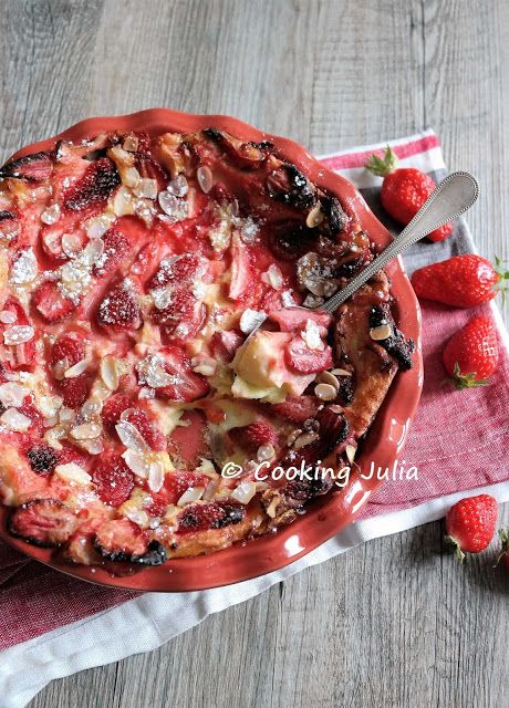 a pie with strawberries and other toppings on a red plate next to some strawberries