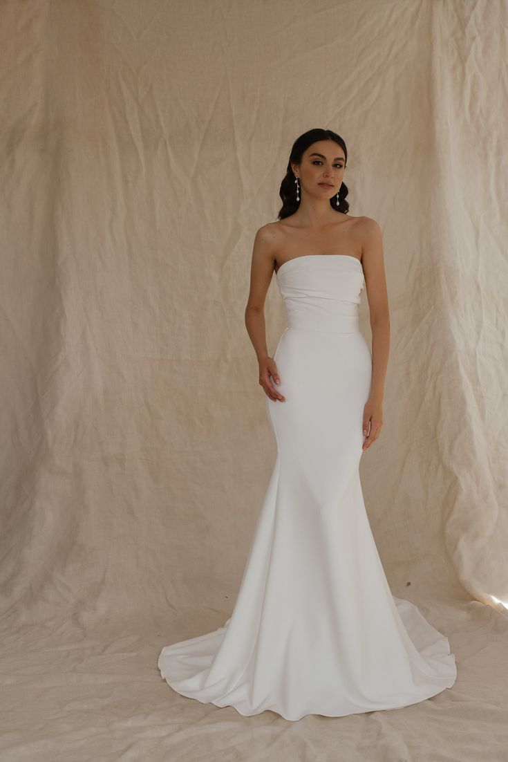 a woman in a white wedding dress posing for a photo with her hands on her hips