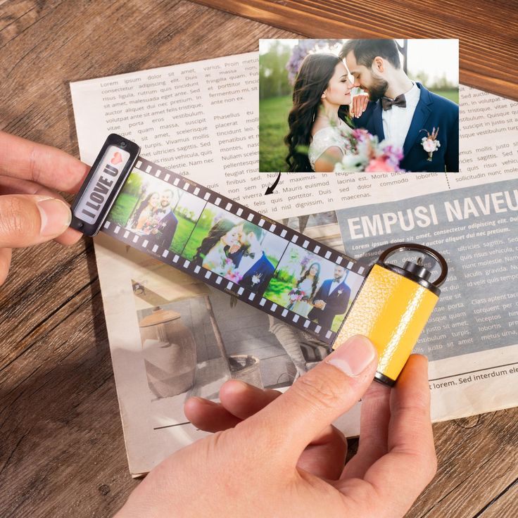 a person is holding a camera keychain with a film strip attached to it