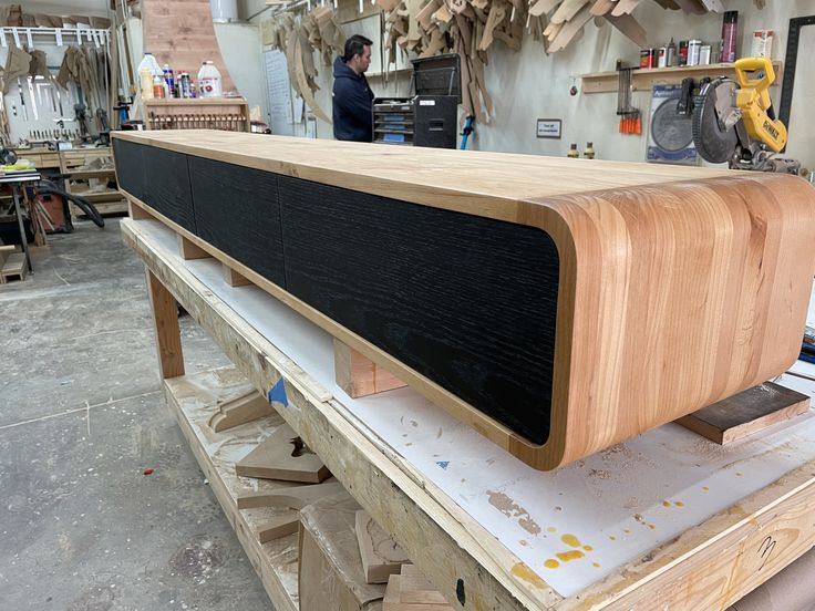 a large wooden speaker sitting on top of a piece of plywood in a shop