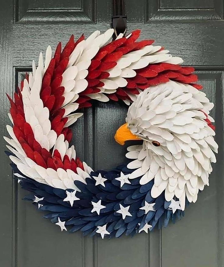 an eagle wreath is hanging on the front door with red, white and blue feathers