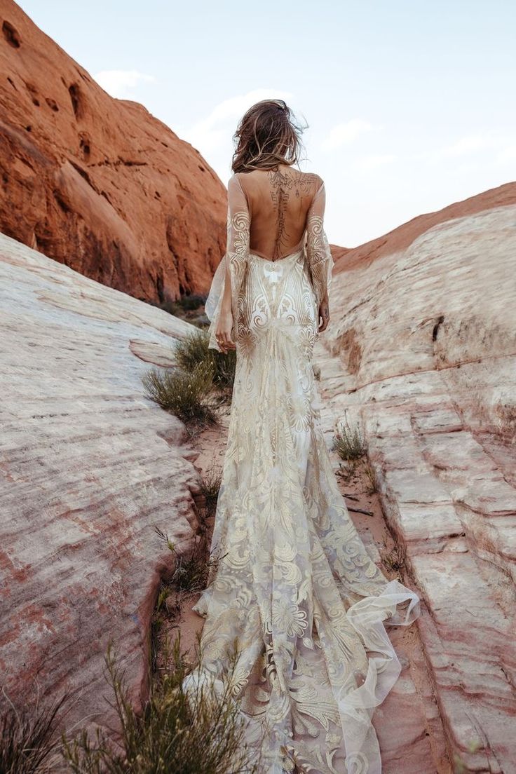 the back of a woman's dress as she walks up some steps in an arid area