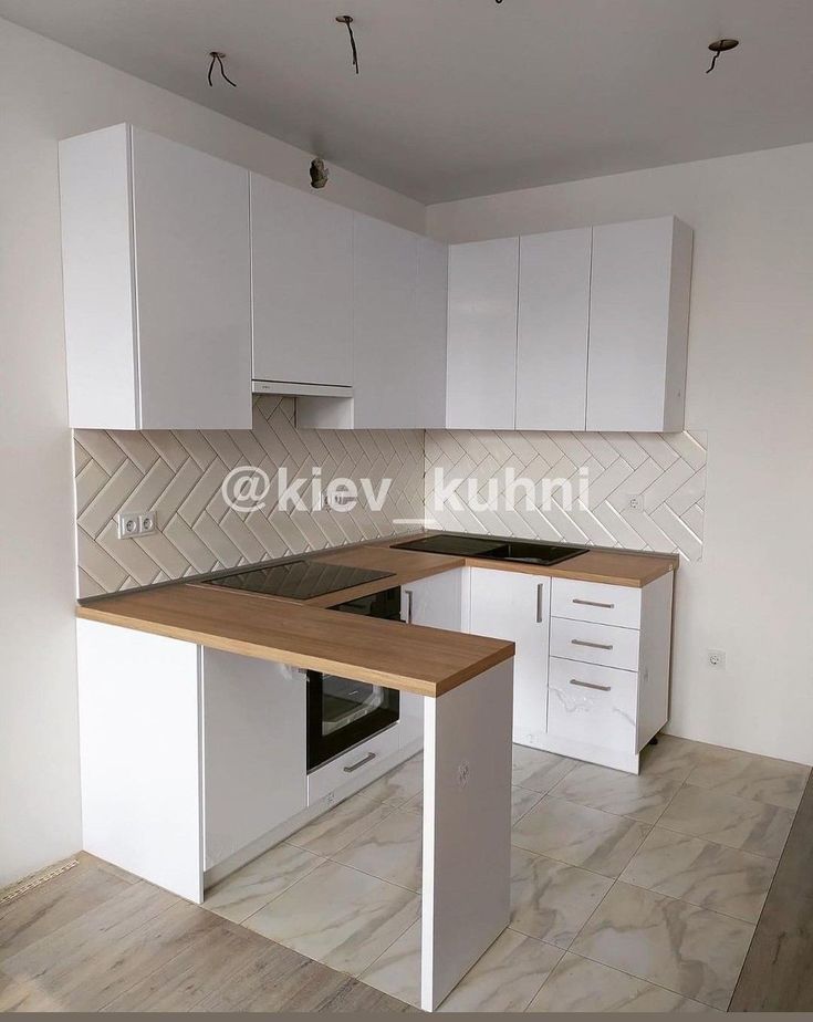 an empty kitchen with white cabinets and wood counter tops in the middle of the room