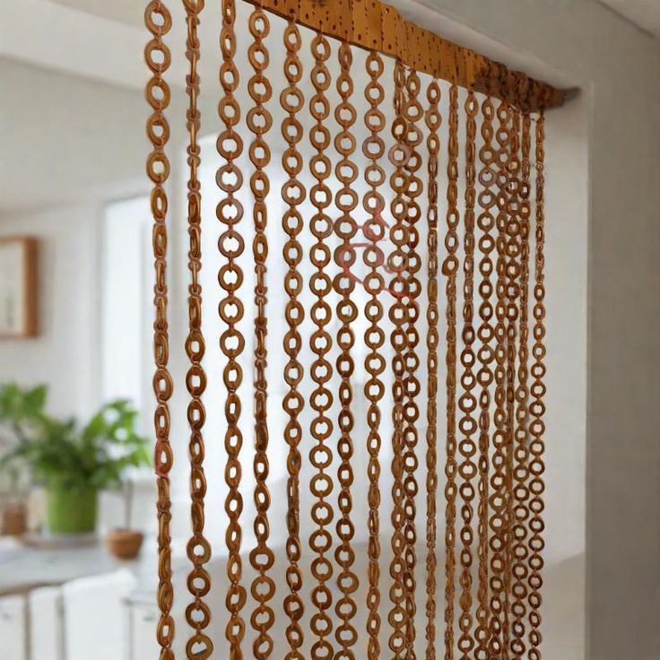 a curtain made out of metal rings hanging from the side of a wall next to a potted plant