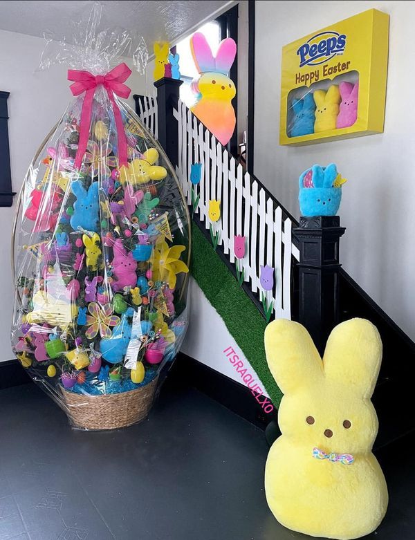 a yellow stuffed animal sitting next to a basket filled with easter eggs and peeps