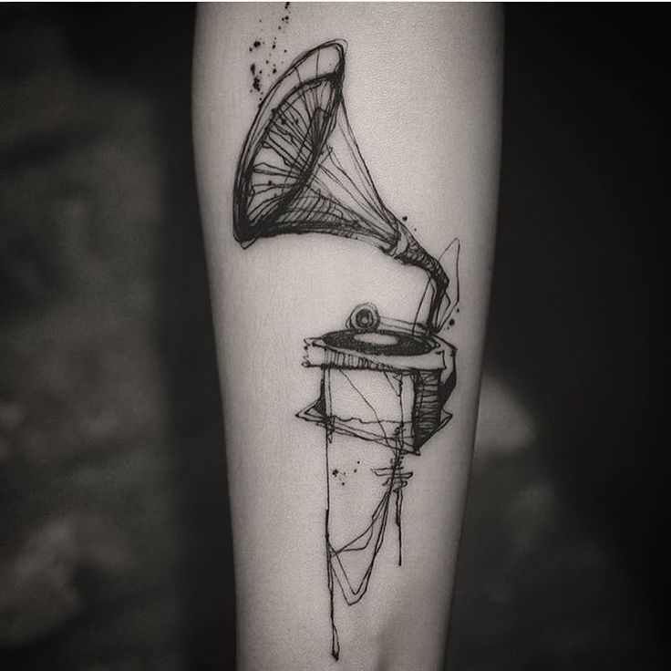 a black and white photo of a person's arm with a musical instrument tattoo on it