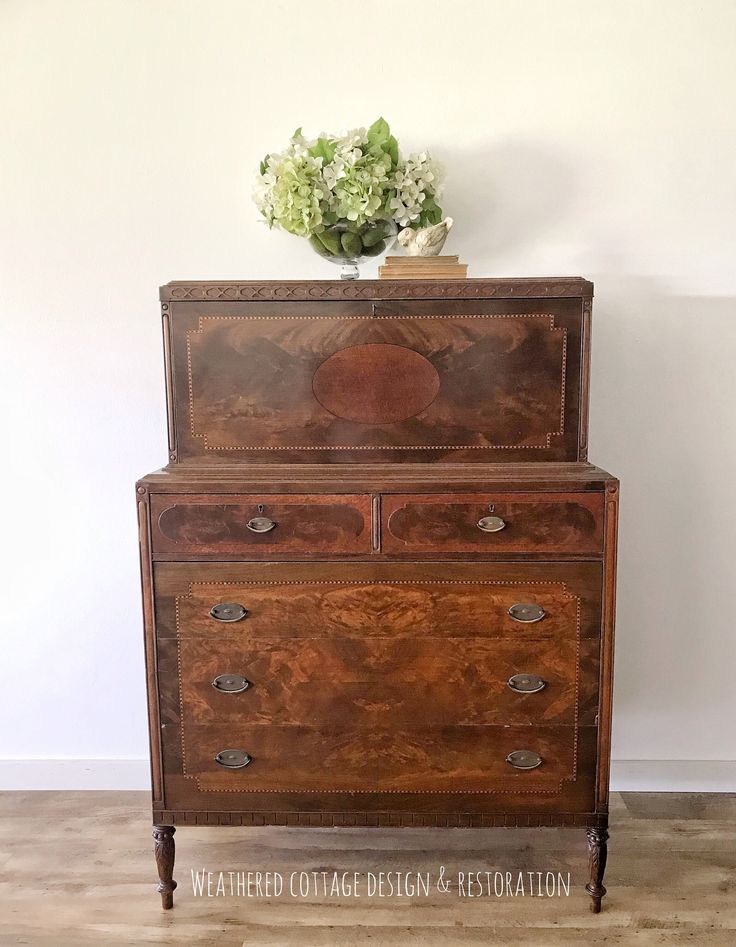 an old wooden dresser with flowers on top